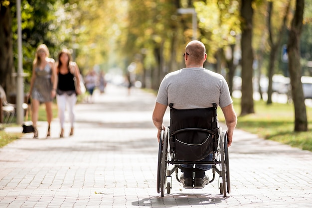 Gehandicapte man in rolstoelwandeling op het steegje van het park
