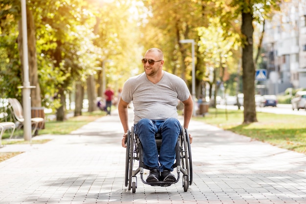 Gehandicapte man in rolstoelwandeling op het steegje van het park