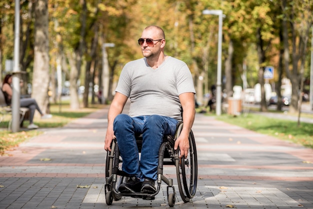 Gehandicapte man in rolstoelwandeling op het steegje van het park