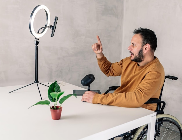 gehandicapte man met één vinger omhoog, filmt zichzelf met een lichtring, voor sociale netwerken