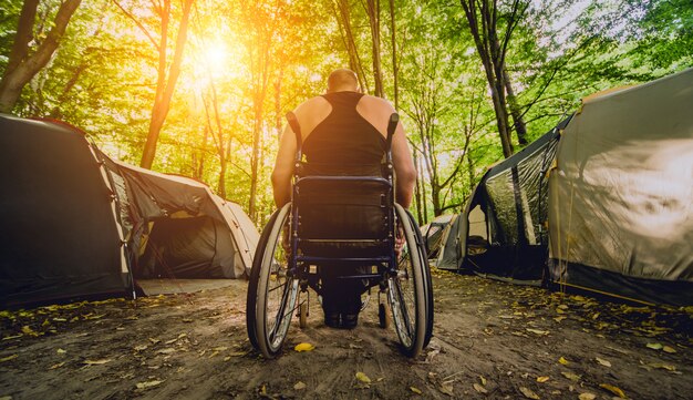 Gehandicapte man rusten op een camping met vrienden. Rolstoel in het bos