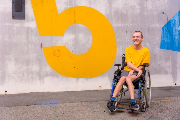 Gehandicapte persoon in een openbaar park in een rolstoel met een gele t-shirt glimlachend