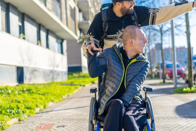 Gehandicapte persoon in een rolstoel lachend met een vriend in een stoel op straat in de winter