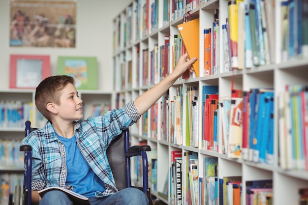 Gehandicapte schooljongen die boek in bibliotheek selecteert