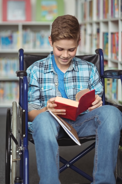 Gehandicapte schooljongen leesboek in bibliotheek