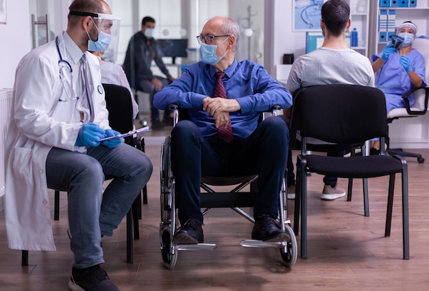 Gehandicapte senior man in rolstoel praten met dokter