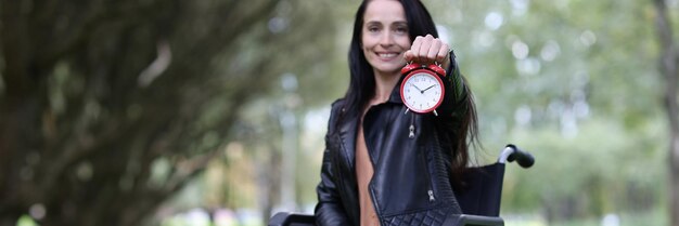 Gehandicapte vrouw in rolstoel met rode wekker in park nieuwe kansen in levens van