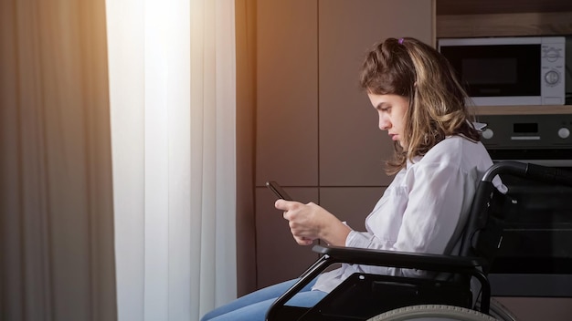 Gehandicapte vrouw in rolstoel probeert thuis smartphone te gebruiken