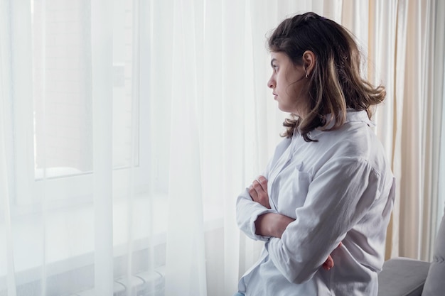 Gehandicapte vrouw met organische schade aan het centrale zenuwstelsel staat thuis bij het raam