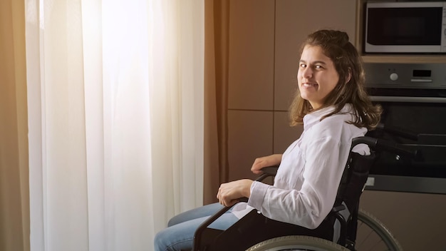 Gehandicapte vrouw zit in een rolstoel thuis naar de camera te kijken
