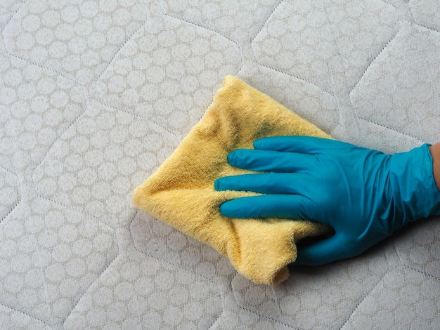 Gehandschoende hand maakt een vuile matras schoon met vlekken