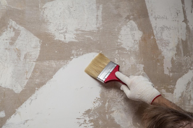 Gehandschoende hand met een borstel op de achtergrond van een stopverfmuur