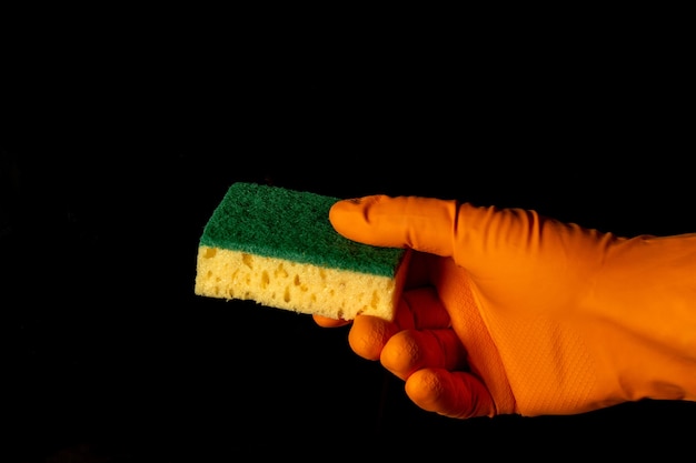 Foto gehandschoende hand met washandje op zwarte achtergrond. het idee van het schoonmaken van gebouwen