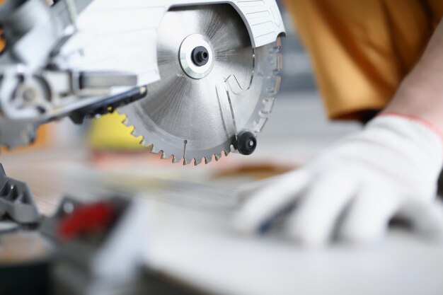 Gehandschoende handen die met een cirkelzaagclose-up werken