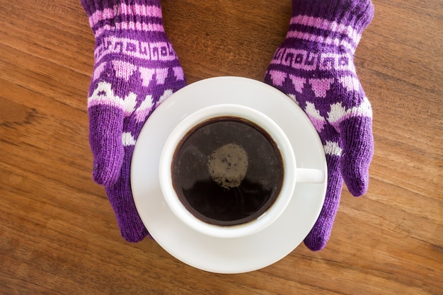 Gehandschoende handen met kopje koffie