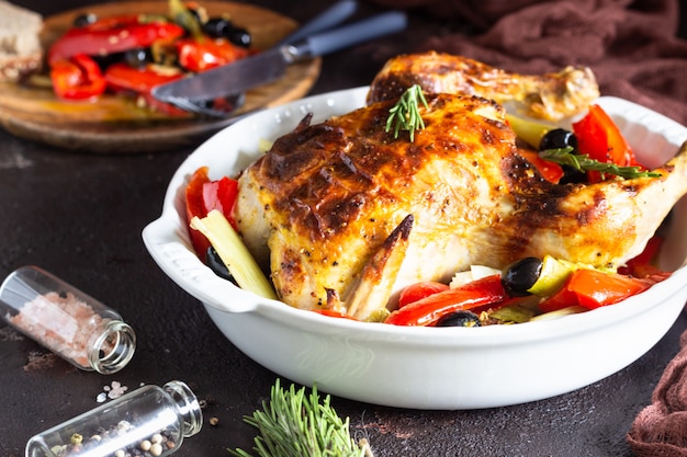 Geheel gebraden kip met groenten in een ovenschaal.