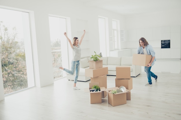 Geïnspireerd mooie dame handen omhoog zingen dansen in witte woonkamer