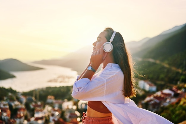 Geïnspireerde gelukkige serene vrouw met gesloten ogen genietend van het luisteren naar rustige muziek met prachtig uitzicht bij zonsondergang Verlichting van stress en een gezonde geest