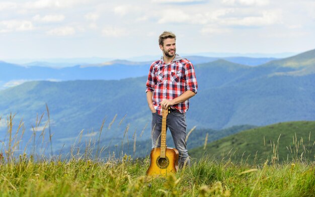 Geïnspireerde muzikant Zomer muziekfestival buiten Muziek spelen Stilte van bergen en geluid van gitaarsnaren Hipster muzikant Inspirerende omgeving Man muzikant met gitaar op topberg