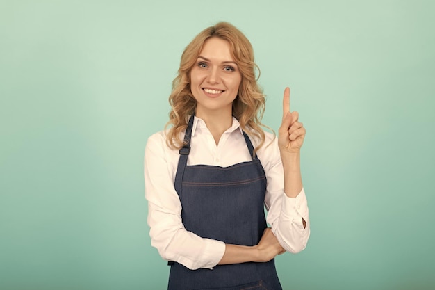 Geïnspireerde vrouw in schort wijzende vinger huisvrouw uiten geluk positieve emoties