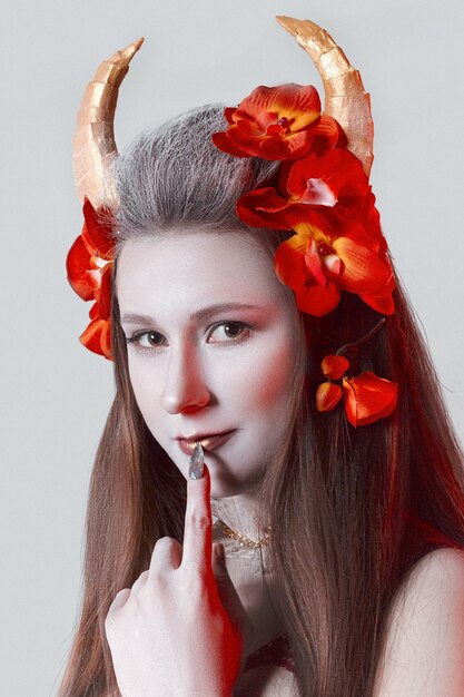Geisha with horns and red flowers on white background in red\
bra. young woman face portrait.