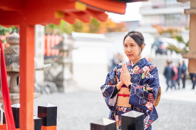 赤い木製の鳥門の中で日本の着物を着ている芸者の女の子