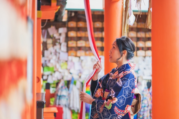 赤い木製の鳥門の中で日本の着物を着ている芸者の女の子