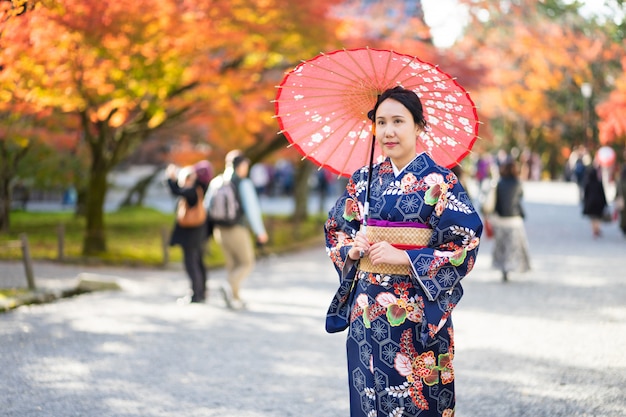 赤い木製の鳥門の中で日本の着物を着ている芸者の女の子