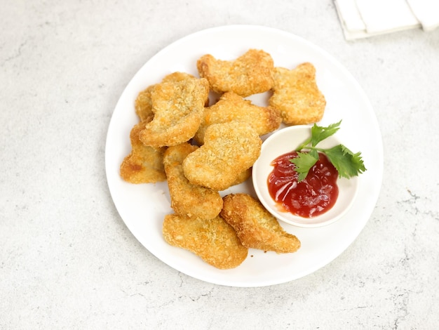 Geïsoleerd een bord kipnuggets geserveerd met tomatensaus op witte achtergrond