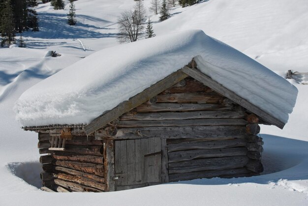 Geïsoleerd houten berghuis bedekt met sneeuw