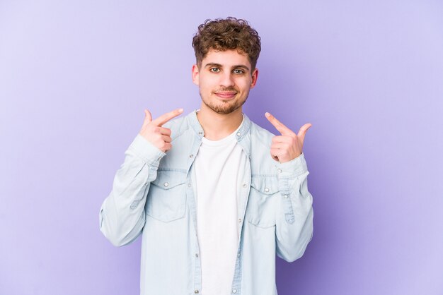 Geïsoleerd jonge blonde krullend haar blanke man glimlacht, wijzende vingers naar de mond.