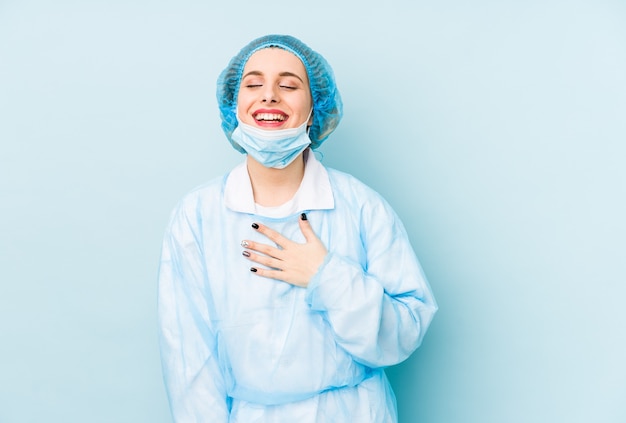 Geïsoleerd jonge chirurg vrouw lacht hardop hand op de borst te houden.