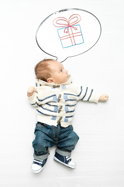 Geïsoleerde foto van schattige kleine babyjongen die droomt van een cadeau