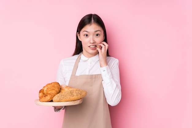 Geïsoleerde jonge chinese bakkersvrouw bijtende vingernagels, zenuwachtig en zeer angstig.