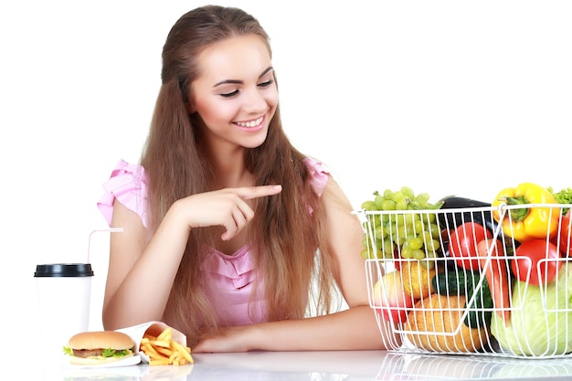 Geïsoleerde jonge vrouw met een mand met groenten, geen fast foodon