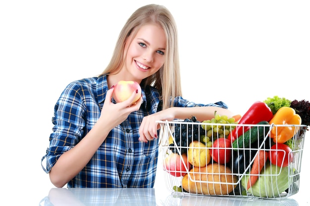 Geïsoleerde jonge vrouw met mand met groenten op lichte backgraund
