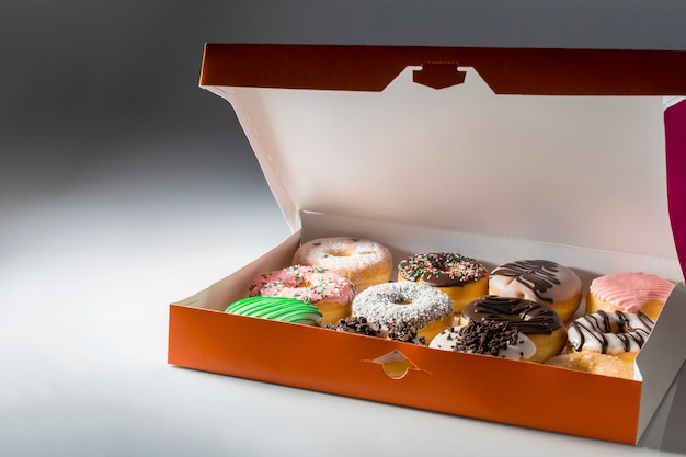 Geïsoleerde Oranje doos met gesorteerde donuts op neutrale achtergrond