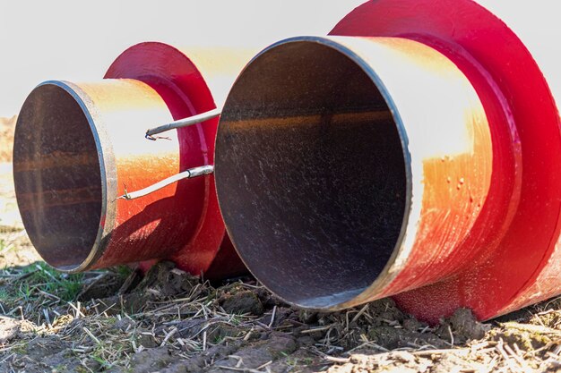 Geïsoleerde pijp Grote metalen pijpen met een plastic omhulsel op een bouwplaats Moderne pijpleiding voor het leveren van warm water en verwarming aan een woonwijk Close-up