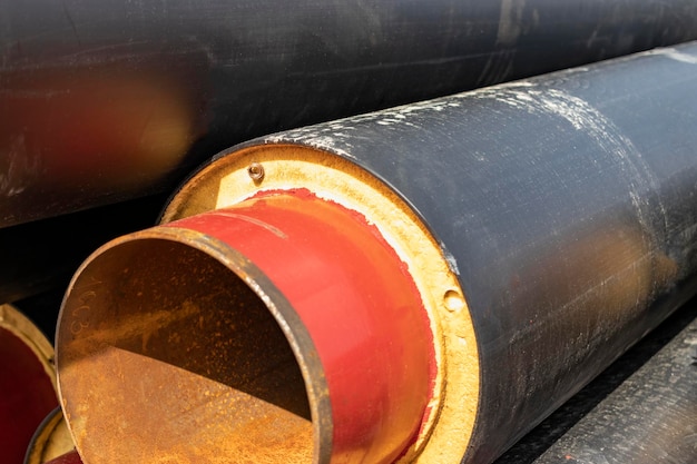 Geïsoleerde pijp Grote metalen pijpen met een plastic omhulsel op een bouwplaats Moderne pijpleiding voor het leveren van warm water en verwarming aan een woonwijk Close-up