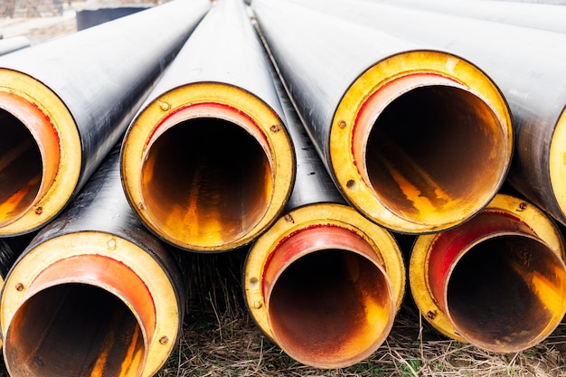 Geïsoleerde pijp Grote metalen pijpen met een plastic omhulsel op een bouwplaats Moderne pijpleiding voor het leveren van warm water en verwarming aan een woonwijk