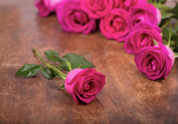 Geïsoleerde roze rozen bloeien op een houten tafel