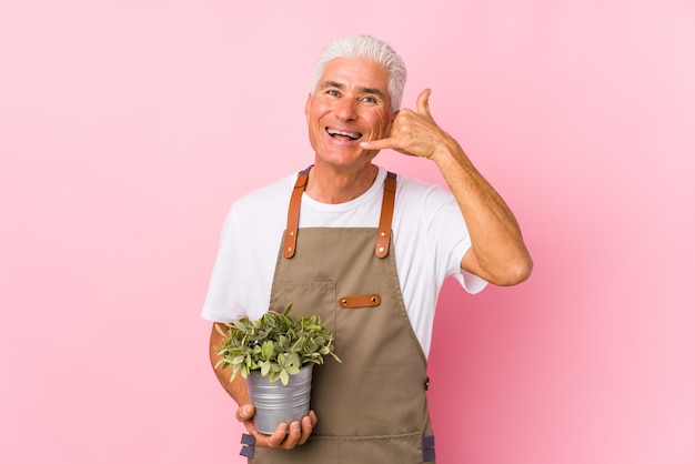 Geïsoleerde tuinman man van middelbare leeftijd met een gebaar van de mobiele telefoongesprek met vingers.