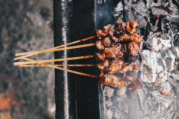 Geitensaté op rood vuur grillen door mensen traditioneel Indonesisch eten gemaakt van schapenvlees