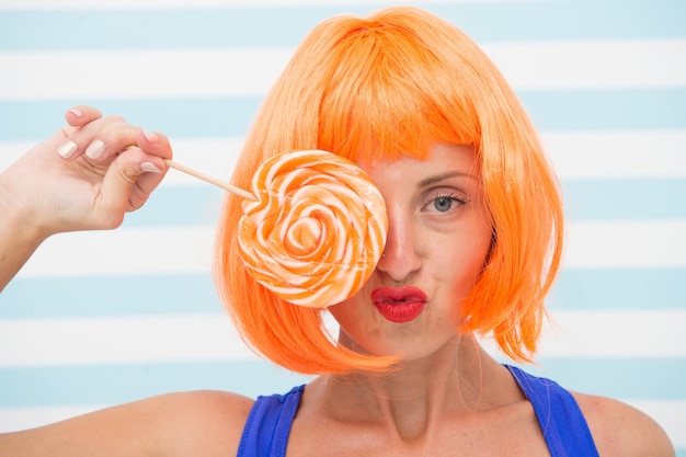 Gek meisje houden en spelen met lolly. dieet concept. lolly dieet. gek meisje houdt van zoete lolly. reclame voor snoepwinkels. speels meisje met gekke look heeft oranje haar en lolly. op dieet zijn.