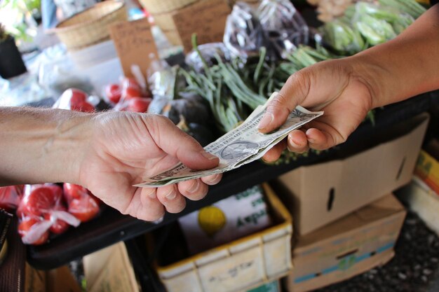 Foto gekapte afbeelding van een hand die contant geld aan een boer betaalt