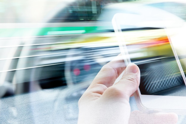 Foto gekapte afbeelding van een hand die een mobiele telefoon vasthoudt in een auto