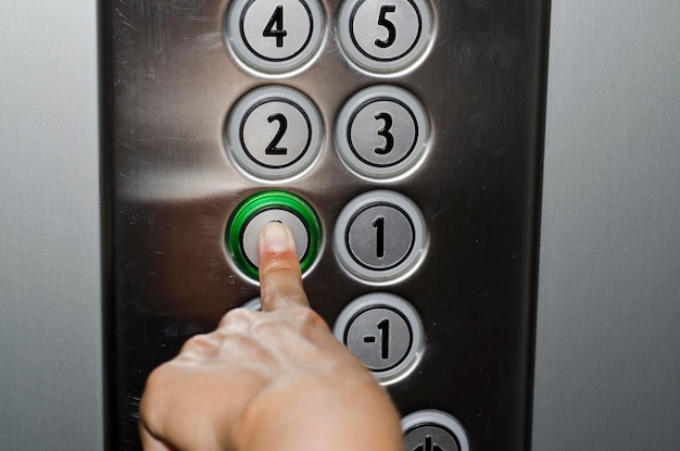 Gekapte afbeelding van een hand die op een knop drukt in een lift