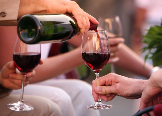 Gekapte afbeelding van een hand die rode wijn in een glas giet