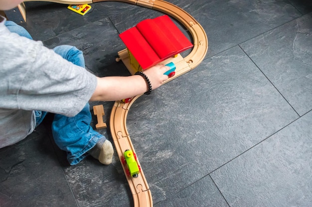 Gekapte afbeelding van een jongen die thuis met een treinstel op de vloer speelt