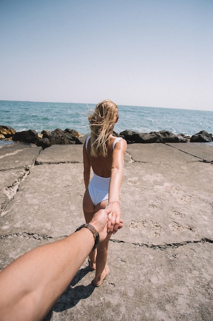 Gekapte afbeelding van een man die een vrouw aan de hand houdt op het strand tijdens een zonnige dag